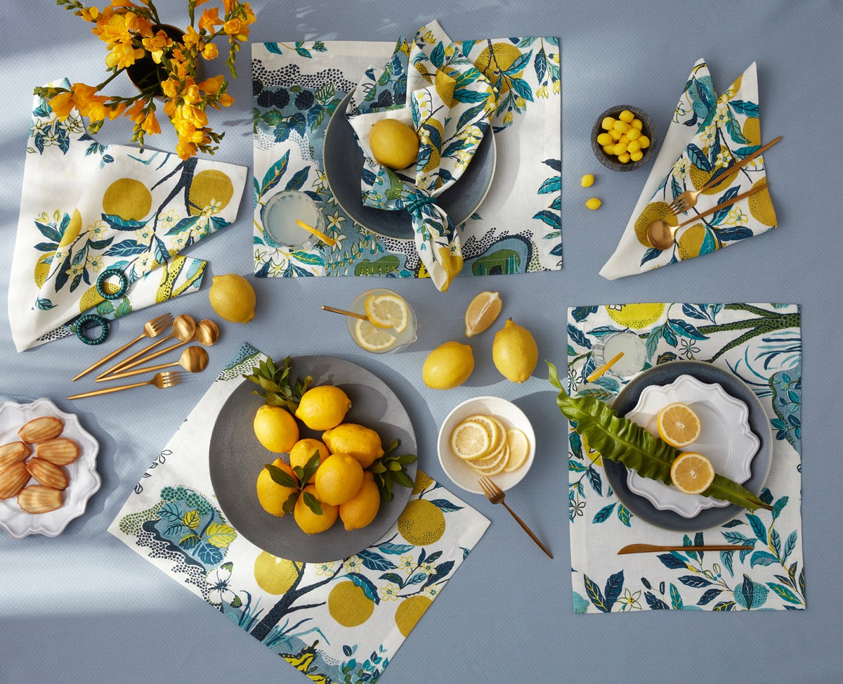 Overhead view of Citrus Garden linen napkins in Pool showcasing lemon-and-teal botanical print and satin-stitched edges