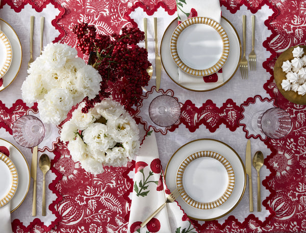 Overhead view of Granada tablecloth in scarlet showing scalloped cutwork border and white floral pattern on a set table