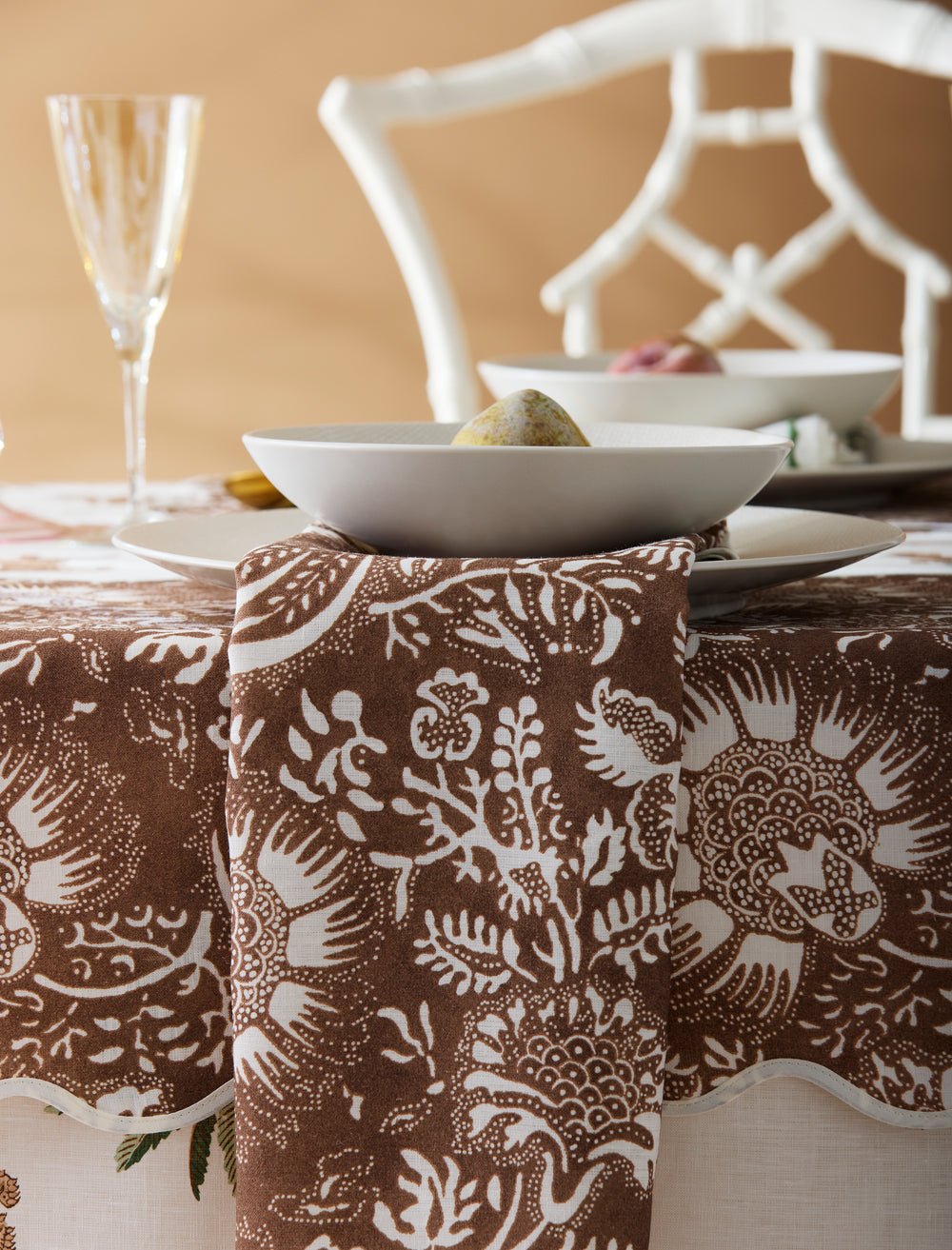 Chestnut Granada placemat under white bowl and plate on styled table with patterned napkin and wine glass in background