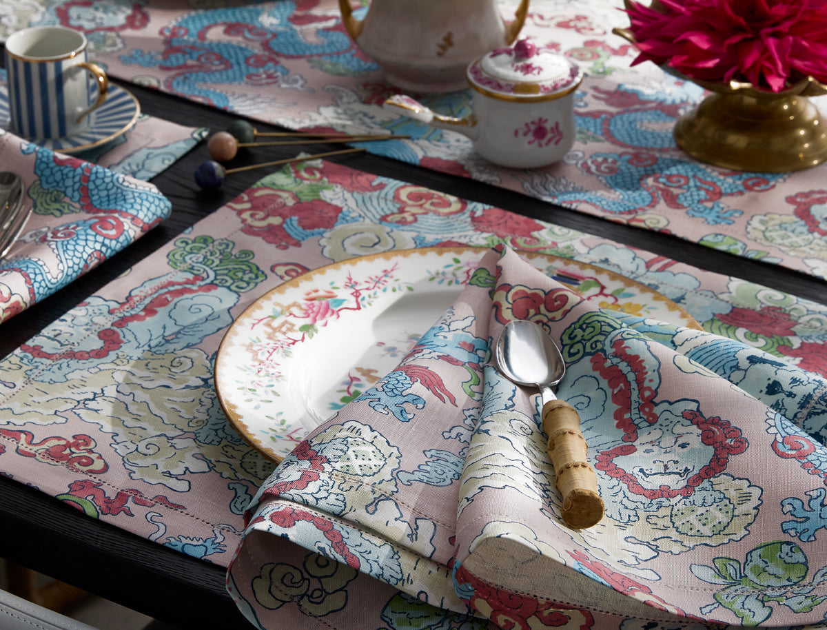 Angled view of Magic Mountain linen napkin folded on a plate showing multicolor dragon and foo-dog print with wave border