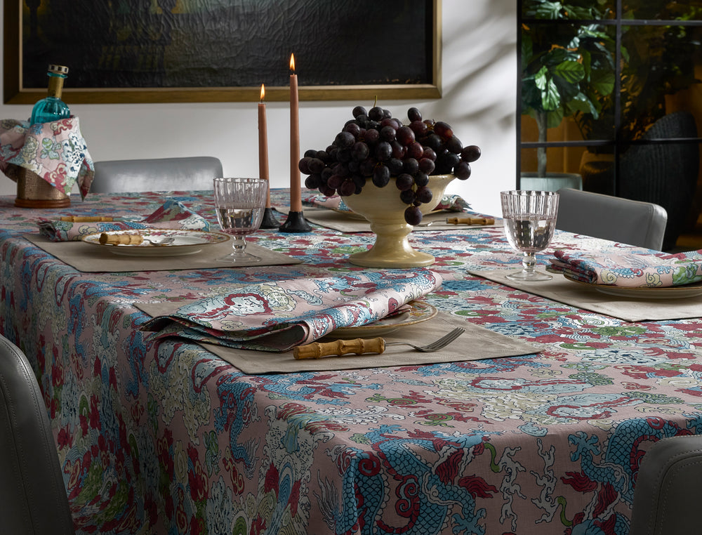 Dining table set with Magic Mountain napkins and matching tablecloth, glassware, lit taper candles, and a bowl of grapes