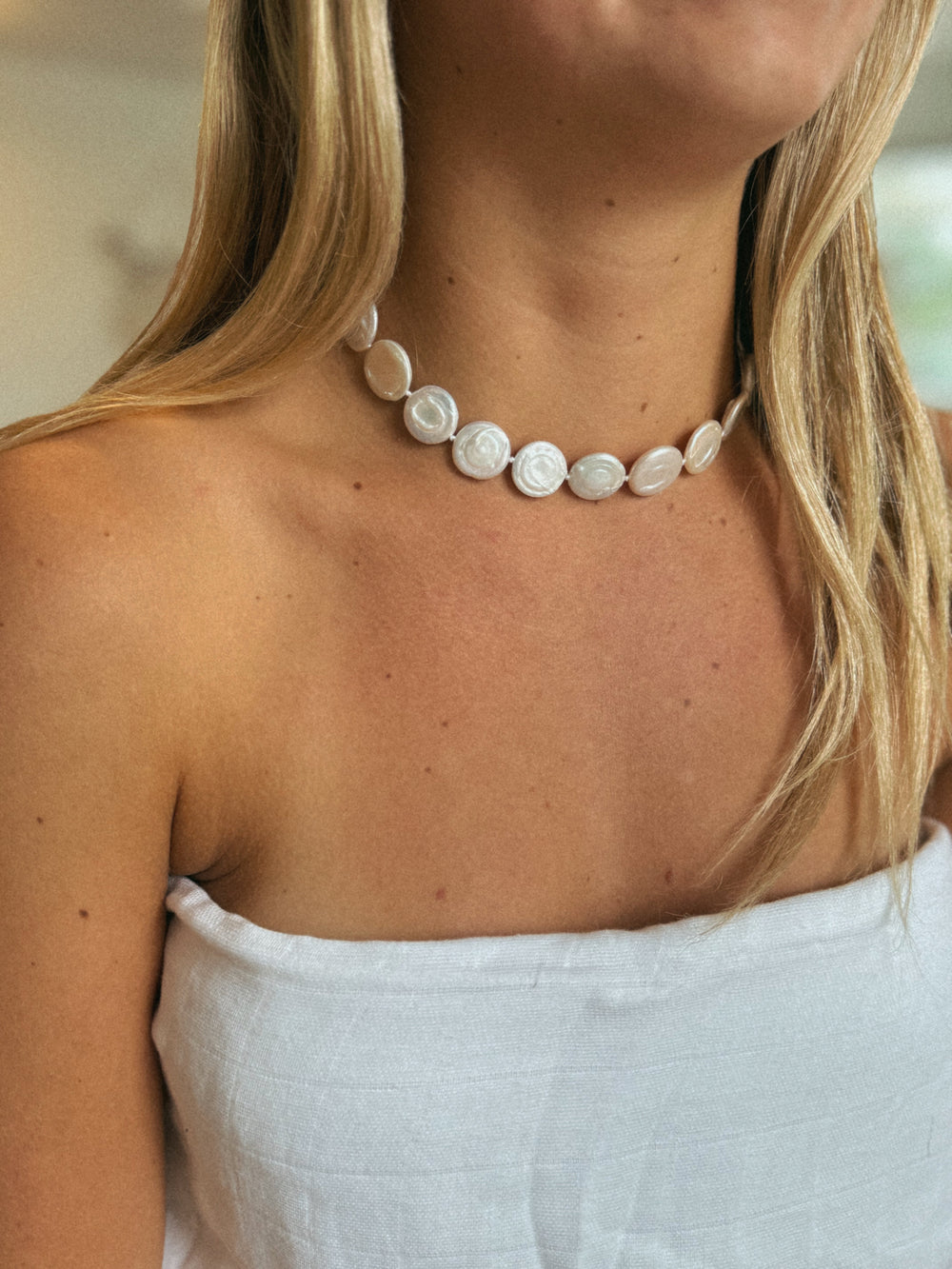 Close-up of The Soulmate Necklace on model showcasing flat round white pearls as a 16-inch choker
