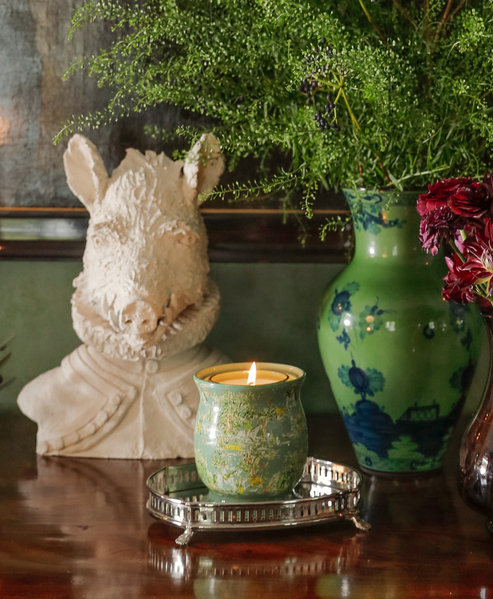 Front view of The Millbrook porcelain vase candle showcasing green scenic equestrian print and lit candle on mirrored tray