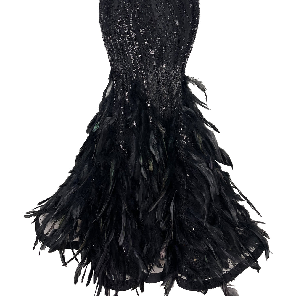Close-up of The Phoenix Feather Dress showing mermaid hem with black feathers and sequin embellishments on white background
