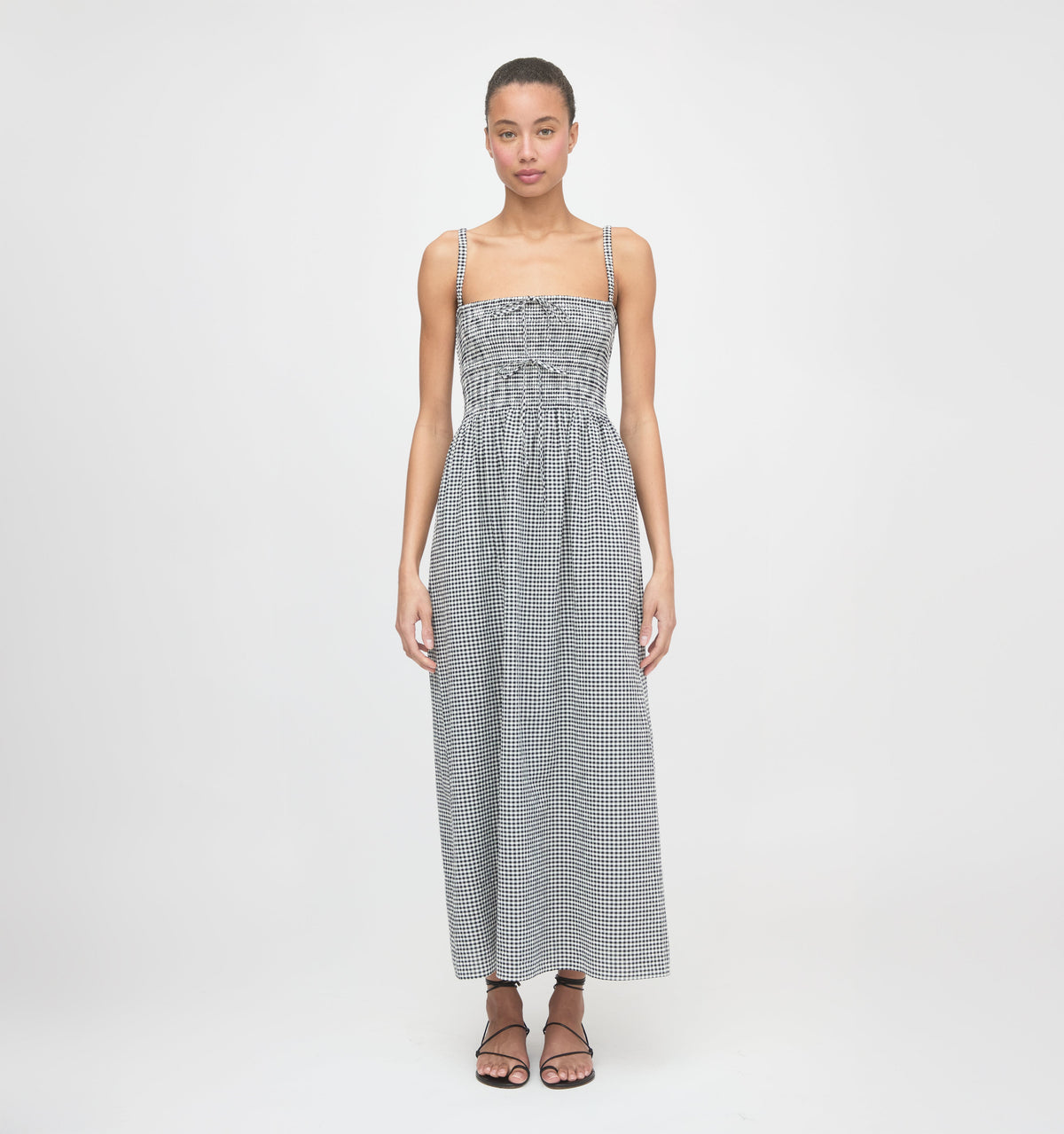 Front view of Larissa Nap Dress in black and sand gingham on model, smocked bodice with adjustable ties, thin straps, maxi skirt
