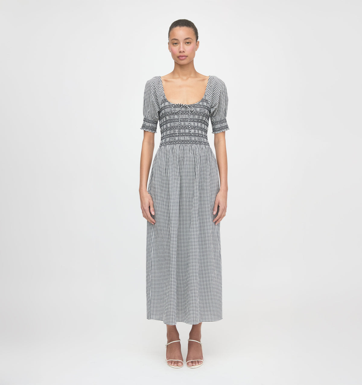 Front view of The Madeline Nap Dress in black and sand gingham with smocked bodice, puff sleeves, scoop neckline on model
