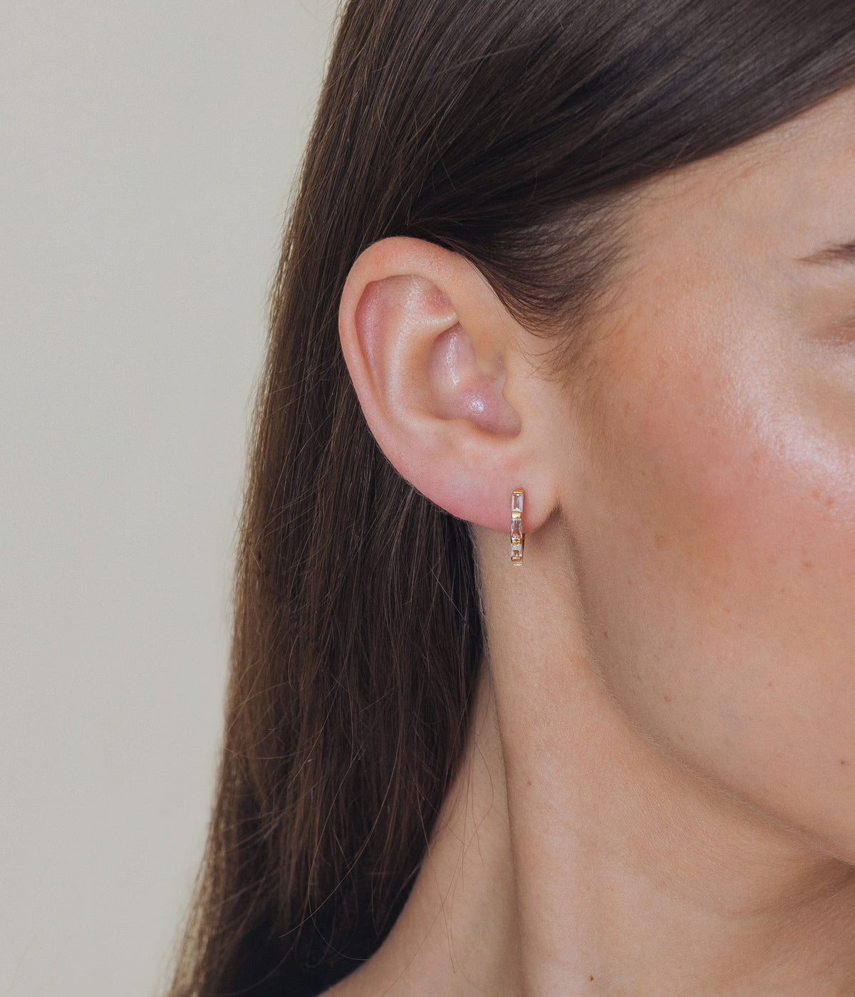 Side view of Thea Hoops showcasing slim baguette embellishments on an ear with a neutral background