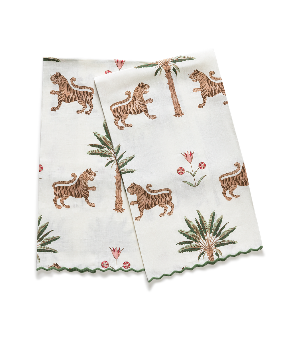 Angled view of Matouk Schumacher Tiger Palm guest towels showcasing tiger, palm, and floral motifs with scalloped green edges on a transparent background