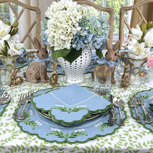 Easter table setting with bunny decorations, floral arrangements, and blue and green plates. Luxury Lilly of the valley placemats