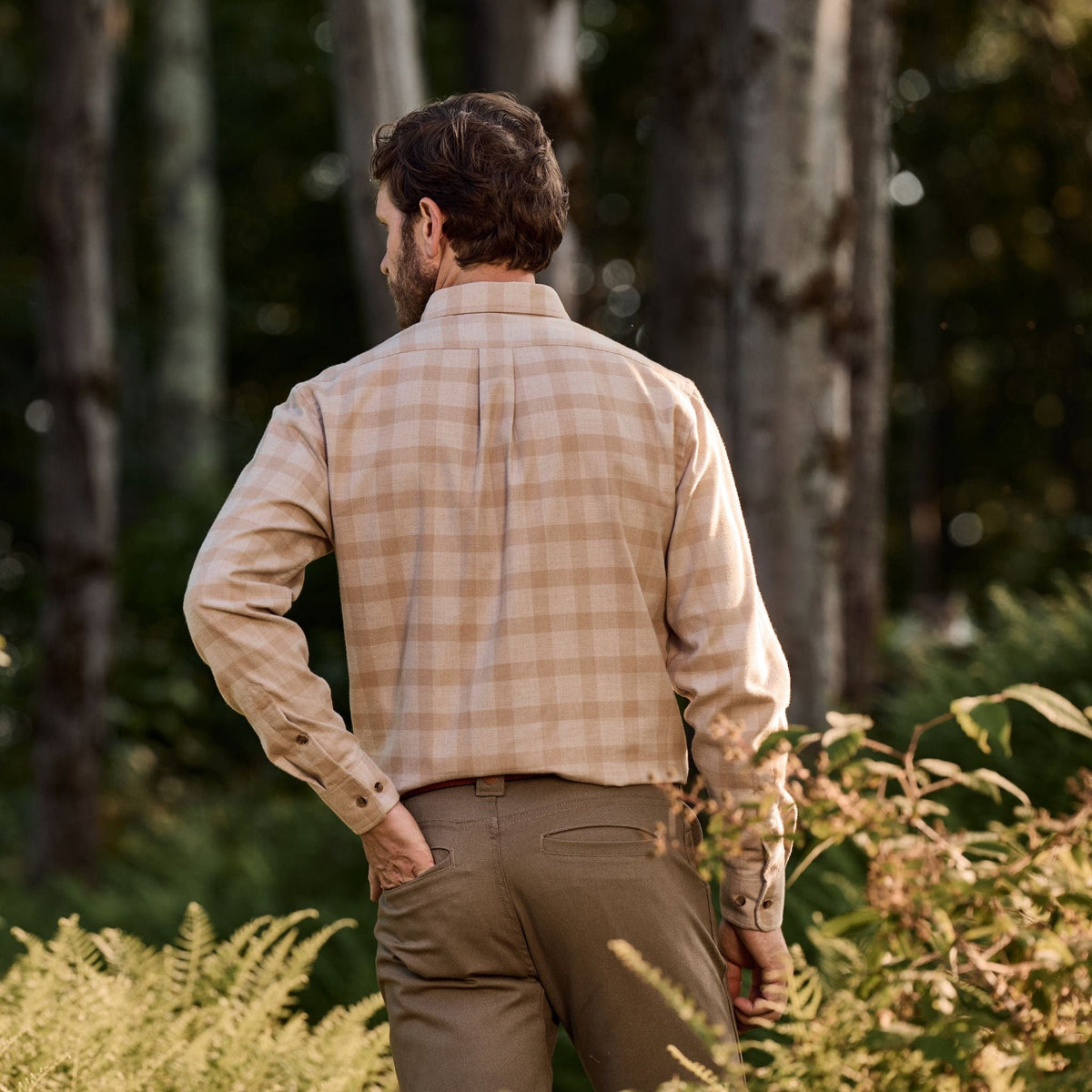 A man stands outdoors among trees wearing the Tom Beckbe Dixon Brushed Cotton Twill Shirt and brown pants.