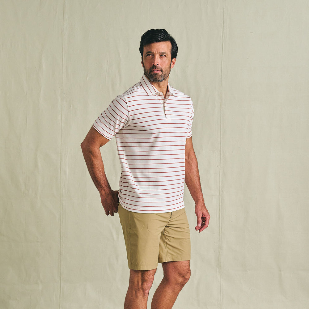Man in Tom Beckbe Crenshaw Performance Short and striped polo stands against a plain background, looking to the side.