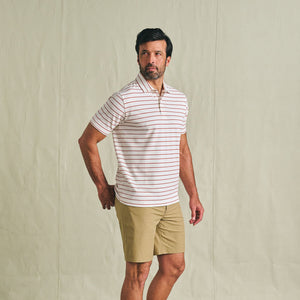 Man in Tom Beckbe Crenshaw Performance Short and striped polo stands against a plain background, looking to the side.