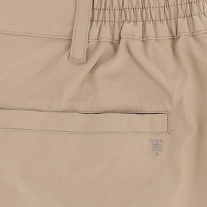 Close-up of Tom Beckbe Crenshaw Performance Short in beige, featuring elastic waistband, belt loop, welt pocket, and logo.
