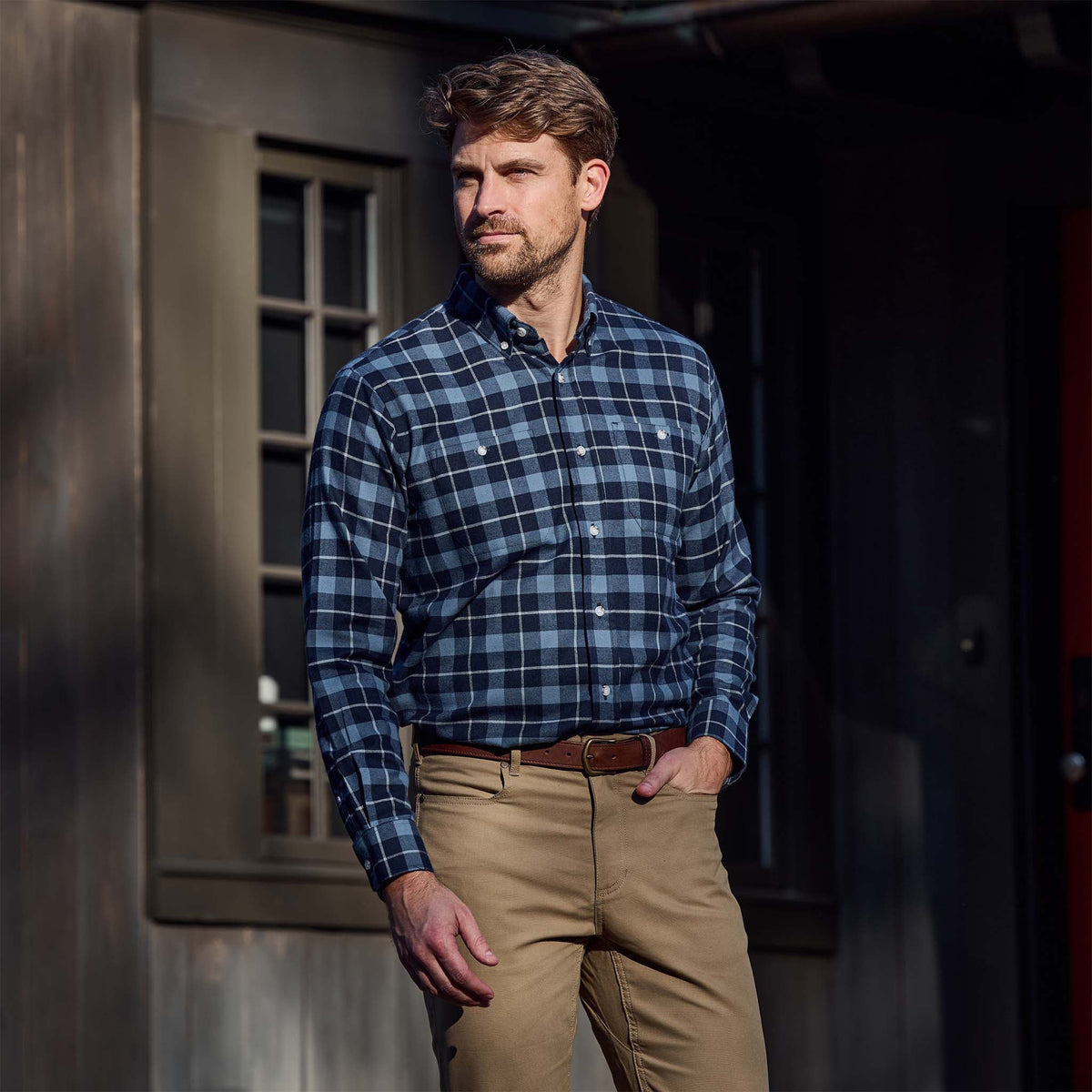Man outdoors in a Tom Beckbe Dixon Brushed Cotton Twill Shirt and khaki pants, hand in pocket near a dark building.