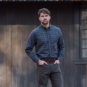 Man in front of a wooden building wears Tom Beckbe's Dixon Brushed Cotton Twill Shirt and gray pants.