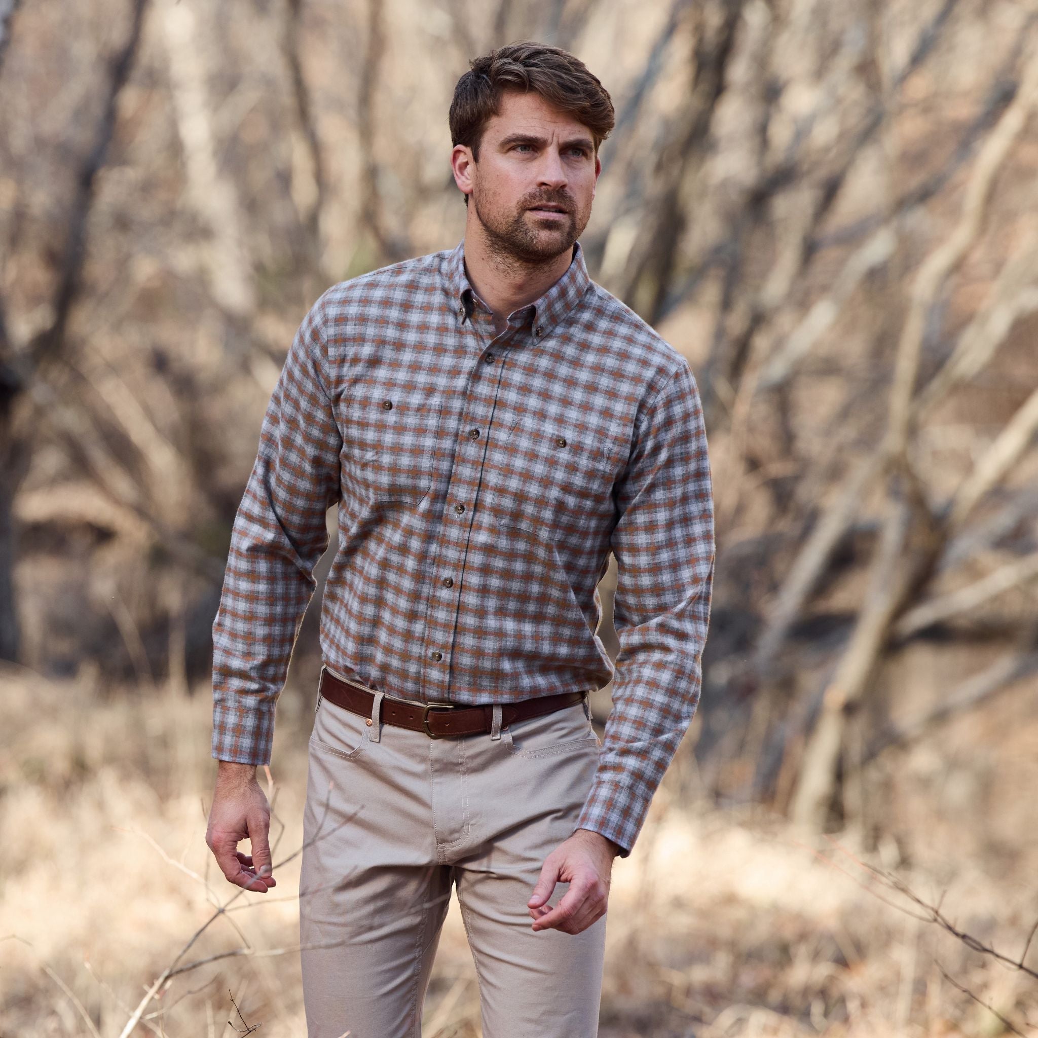 Man wearing a Tom Beckbe Dixon Brushed Cotton Twill Shirt and khaki pants standing outdoors in a dry, wooded area.