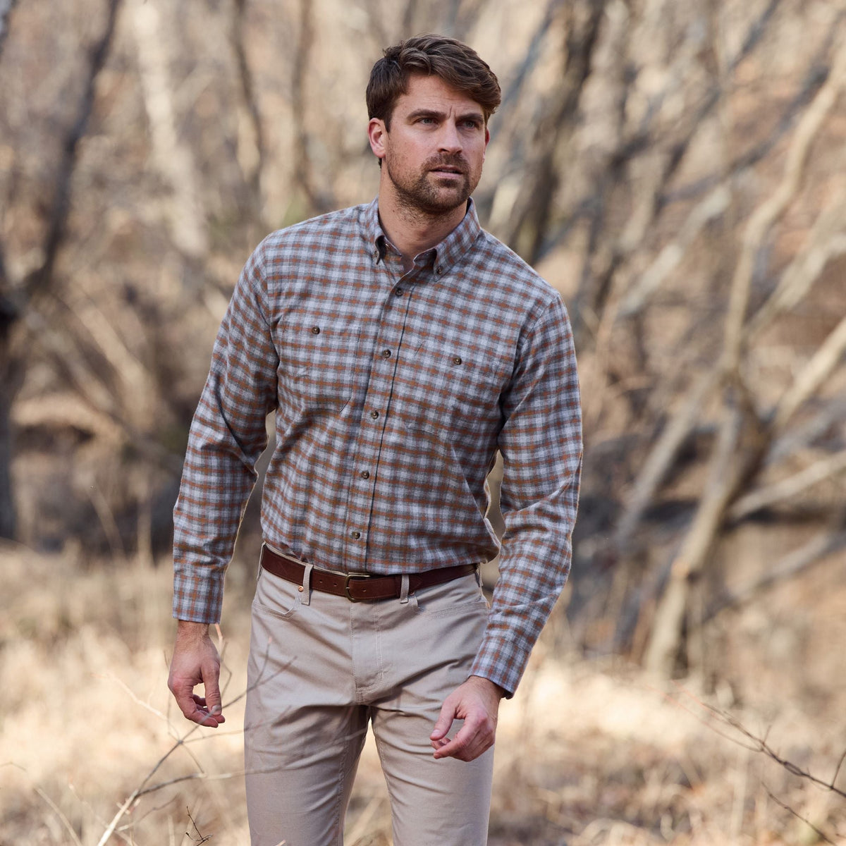 Man wearing a Tom Beckbe Dixon Brushed Cotton Twill Shirt and khaki pants standing outdoors in a dry, wooded area.
