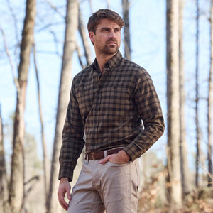 Man wearing a Tom Beckbe Dixon Brushed Cotton Twill Shirt and khaki pants standing in a forest with bare trees.