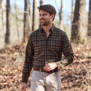 A man in a Tom Beckbe Dixon Brushed Cotton Twill Shirt and beige pants walks outdoors among dry leaves.