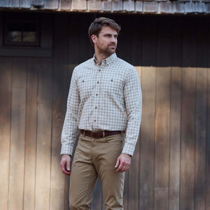 Man wearing the Tom Beckbe Dixon Brushed Cotton Twill Shirt and khaki pants stands outside a wooden building.