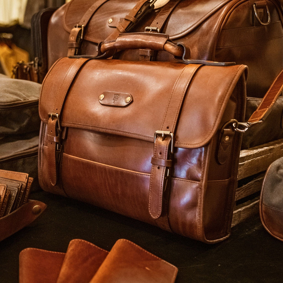 Tom Beckbe Leather Messenger Bag in brown full-grain leather with buckle straps and padded laptop sleeve.