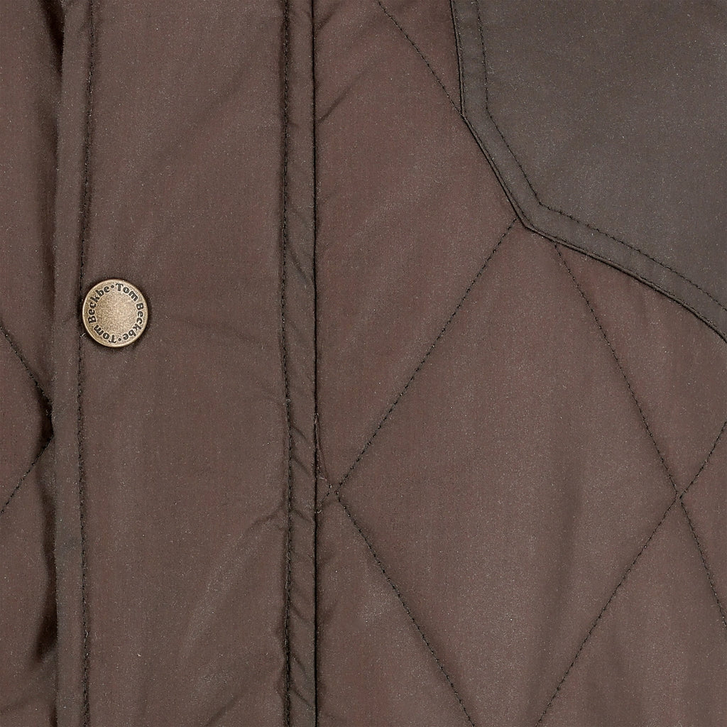 Close-up of the Tom Beckbe Paddock Quilted Jacket with brass snaps and visible stitching, perfect as a weatherproof layer.