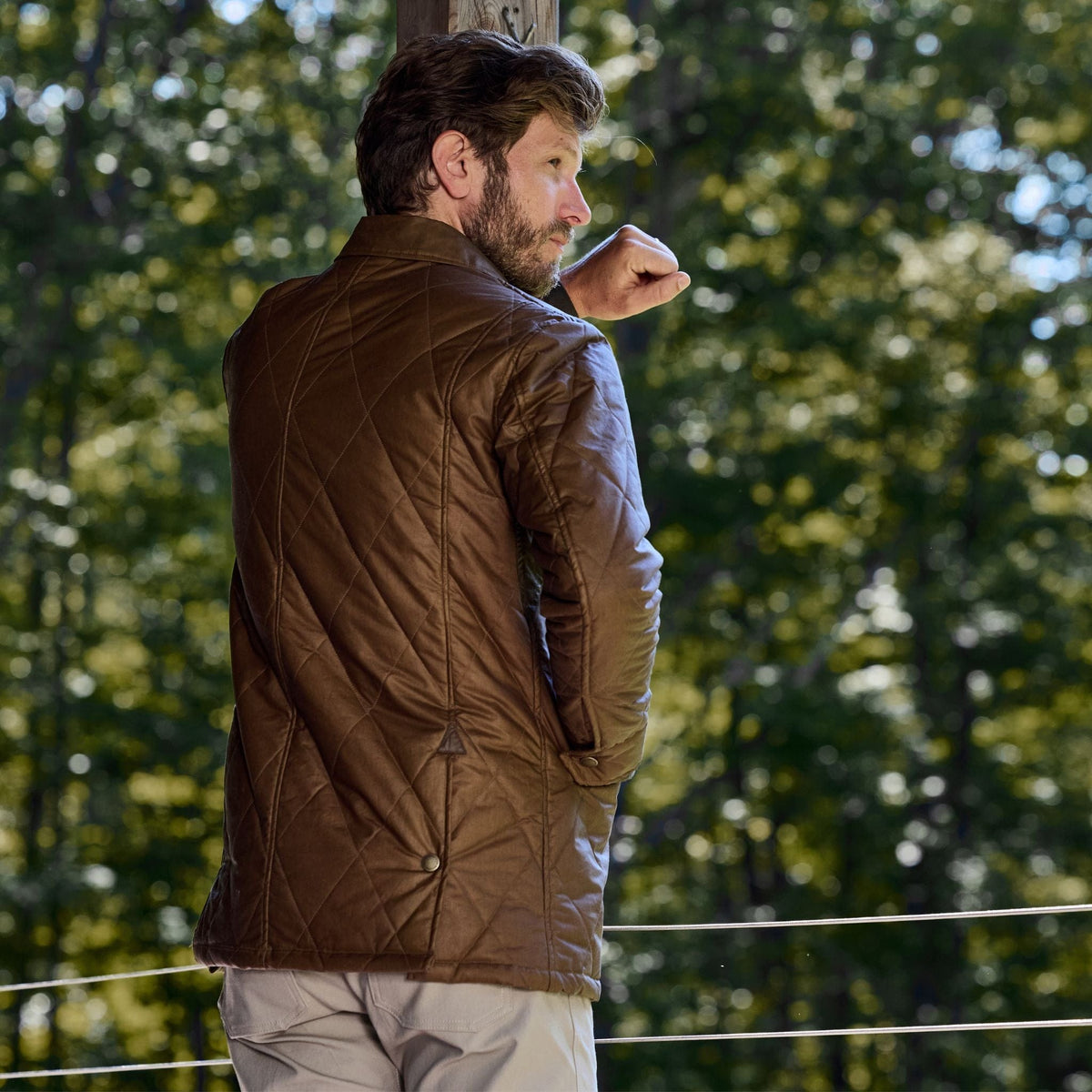 A man outdoors in a Tom Beckbe Paddock Quilted Jacket, epitomizing outdoor wear style.