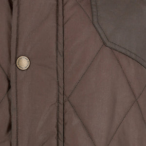 Close-up of the Tom Beckbe Paddock Quilted Vest showing metal snap button and part of the chest pocket.