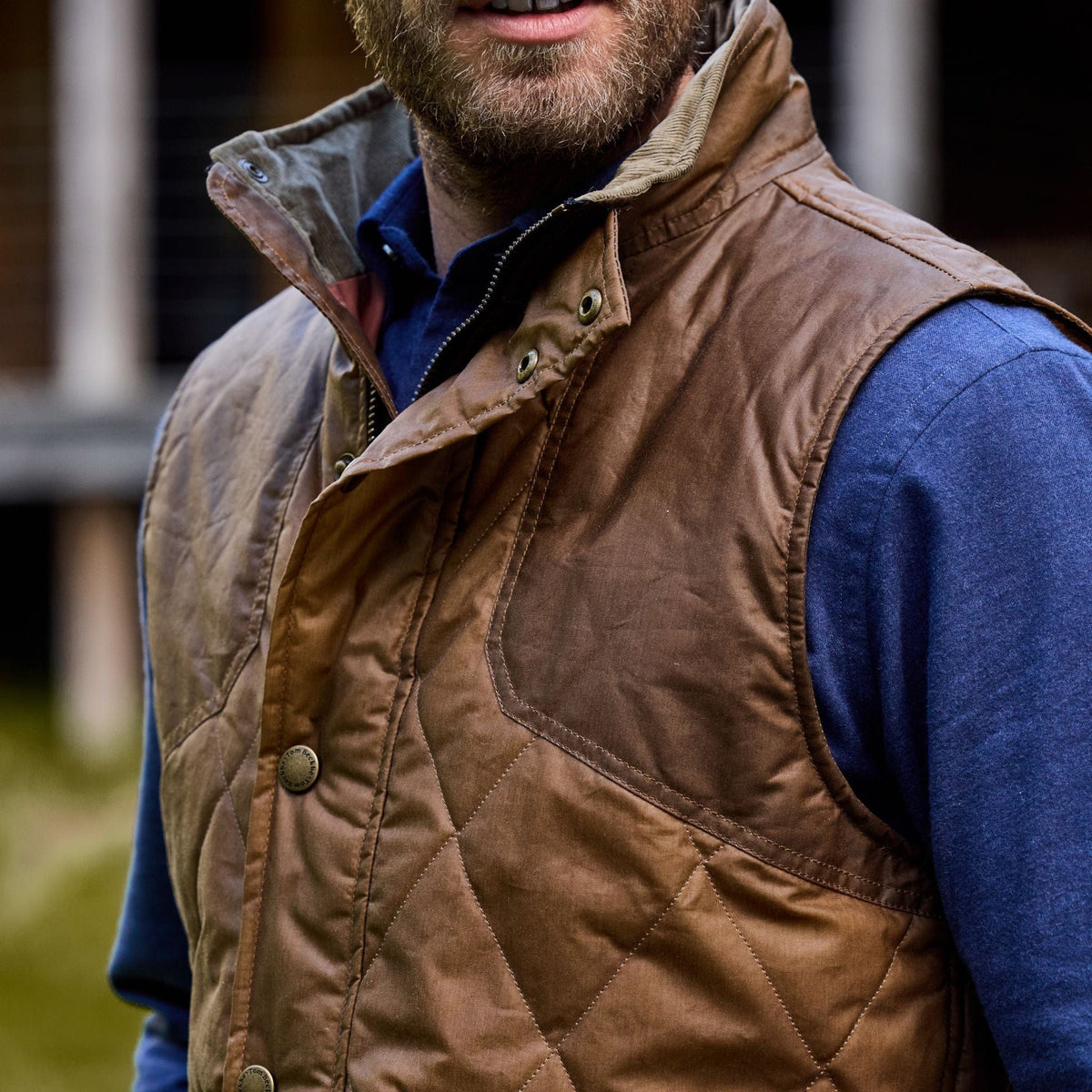 Person in a Tom Beckbe Paddock Quilted Vest over a blue shirt, perfect for the outdoors.