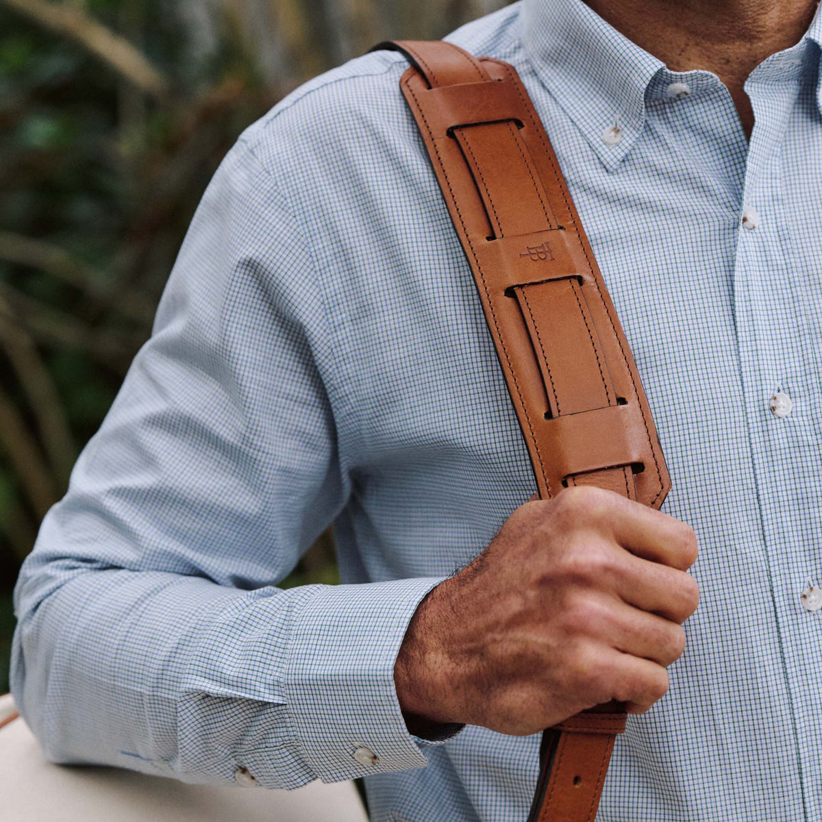 A person in a light blue checkered shirt carries the Tom Beckbe Perdido Canvas Weekender Duffel Bag over their shoulder.