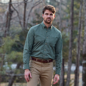 Man in Tom Beckbe Powell Performance Shirt (UPF 30+) and khaki pants stands outdoors in a wooded area.
