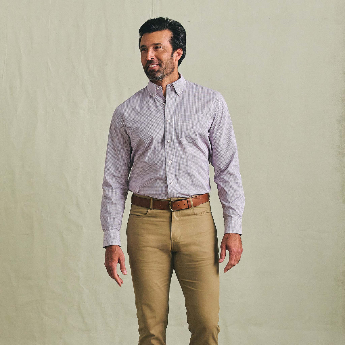 Man in Tom Beckbe Powell Performance Shirt and khaki pants stands against a plain, light background.