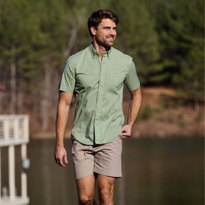 Man in a green short-sleeve shirt and Tom Beckbes Reid Short strolling by a lake.