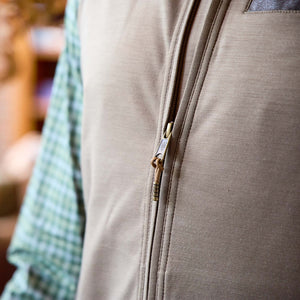 Close-up of the Tom Beckbe Tucker Fleece Vest over a green plaid shirt, featuring its zipper and fabric texture.