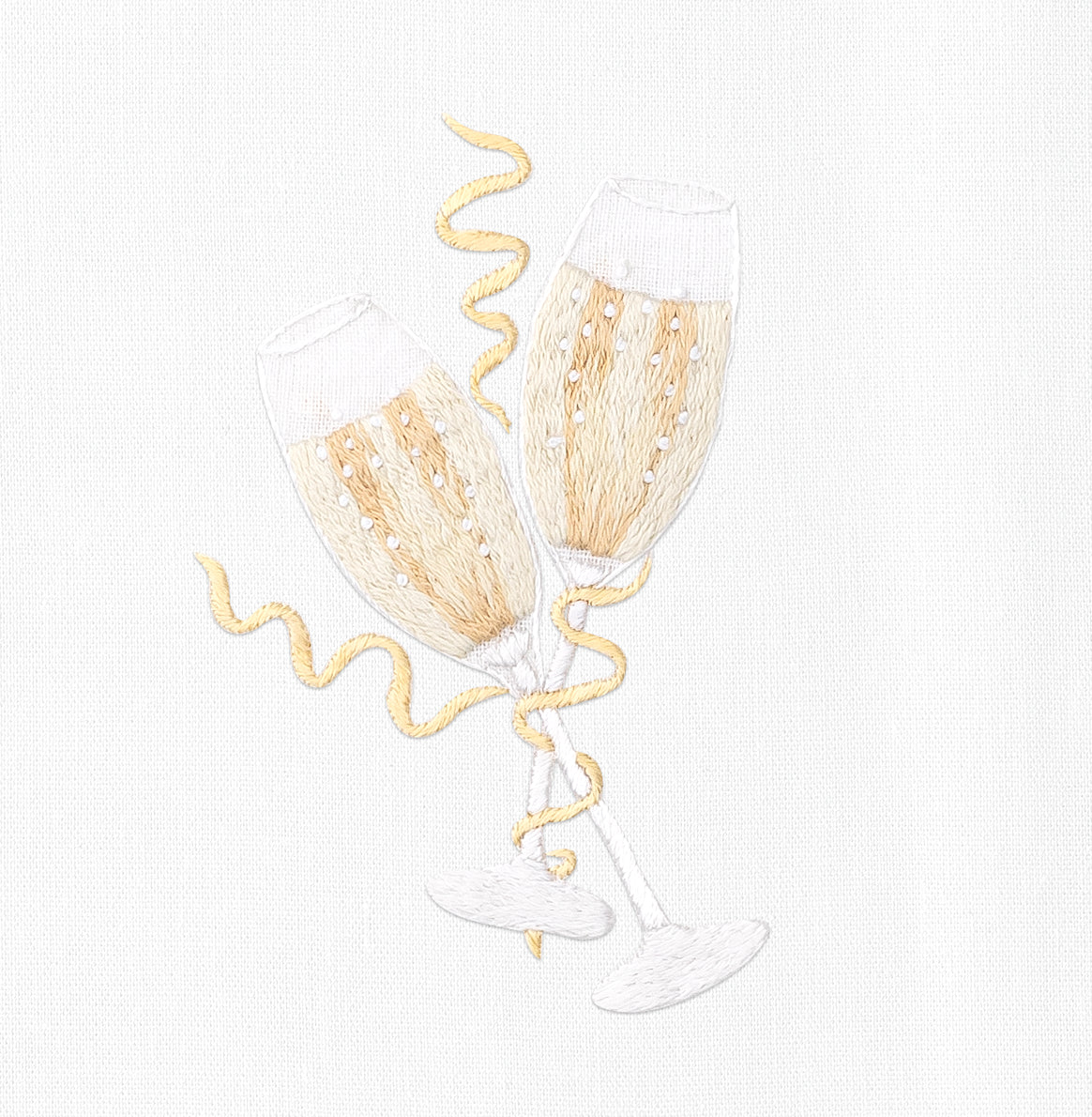 A close up detailed image of the embroidery - Two filled champagne glasses toasting with gold bands wrapped around them.