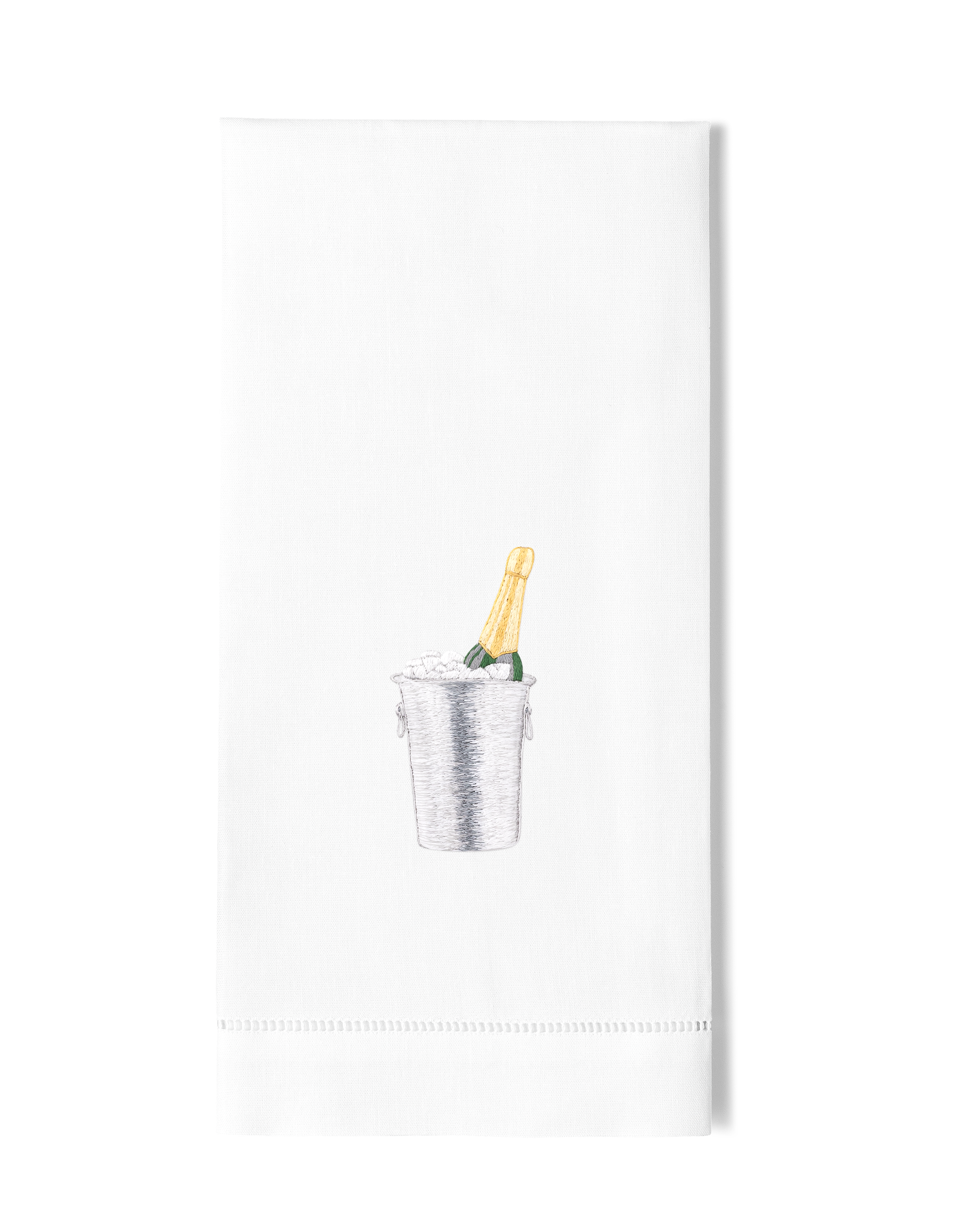 A white hand towel with a hemstitch. A champagne bottle in a silver ice bucket is embroidered in the center.