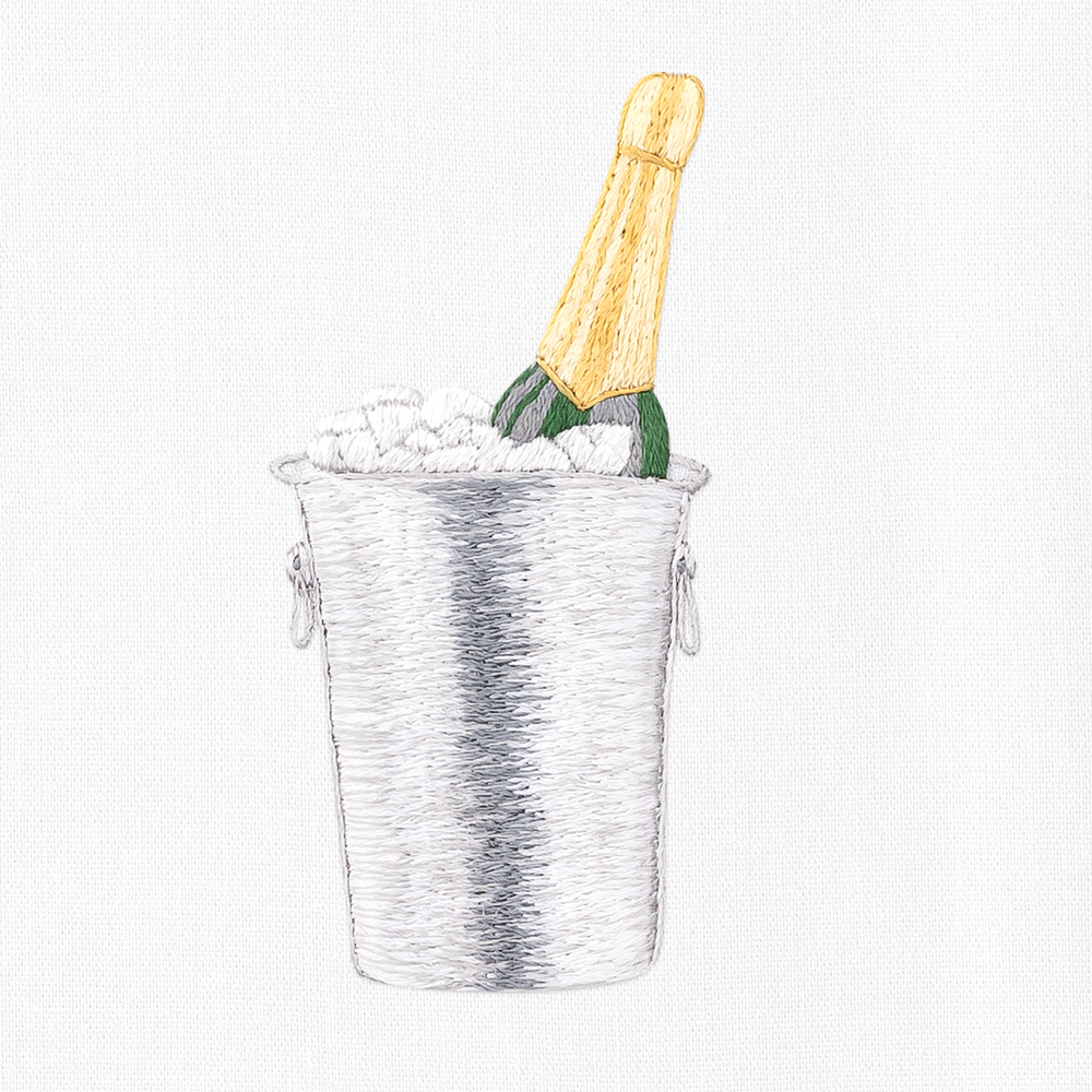 A close up detailed image of the embroidery - A green, gold-capped champagne bottle in a silver ice bucket.