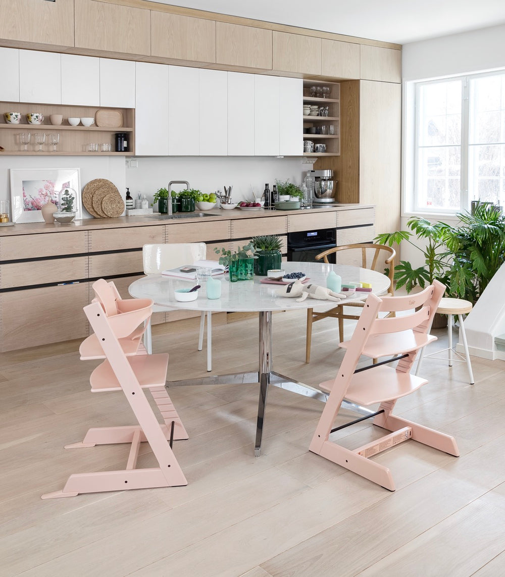 Three-quarter view of Tripp Trapp chair in Serene Pink showing adjustable seat and footrest in a bright kitchen