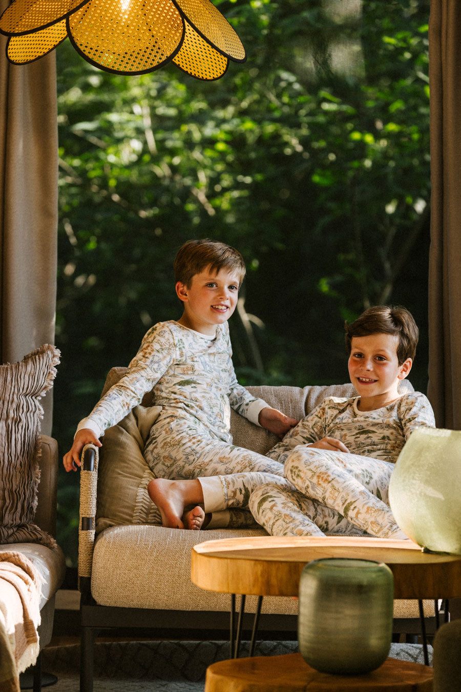Front view of Two Piece Pajamas in Wilderness Spirit on two boys, fitted long-sleeve top and matching pants in a living room