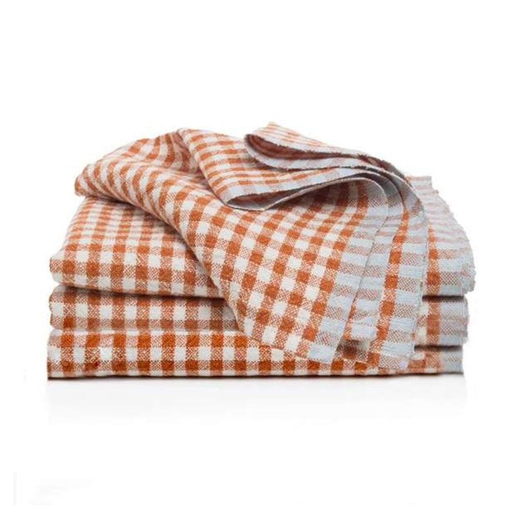 Front-angle view of two-tone gingham linen napkins in cognac and white, folded and stacked, set of 4 on white background