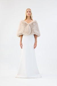 A model viewed from the front wearing a cream faux fur bridal wrap over a white gown.