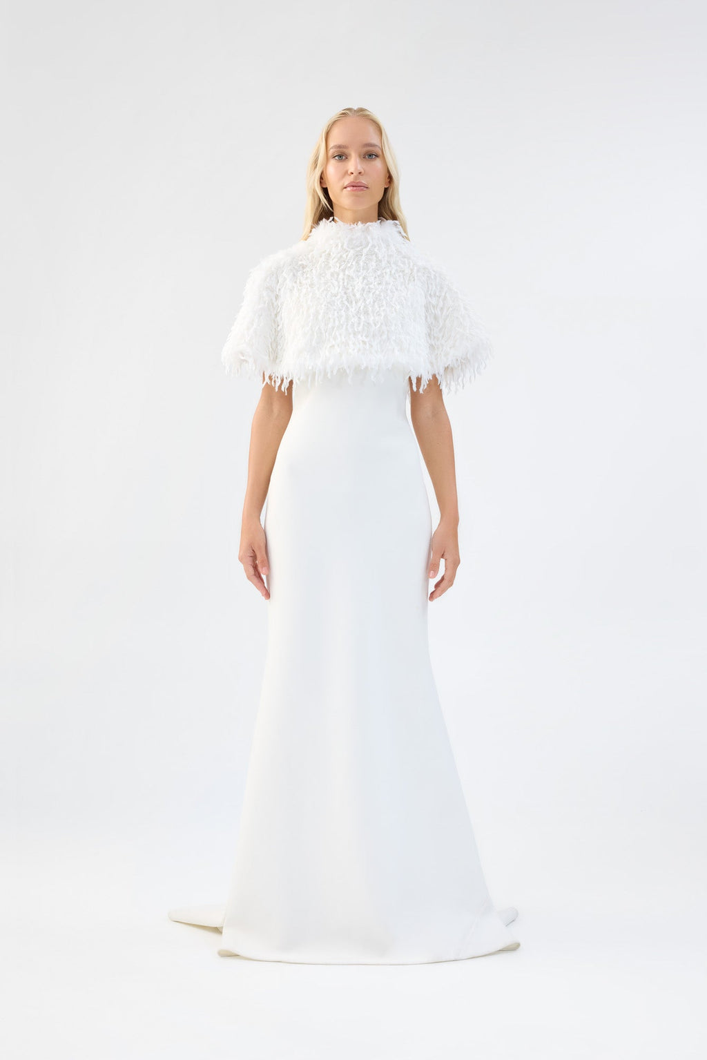 A model viewed from the front wearing a white textured faux fur bridal cape over a white gown.