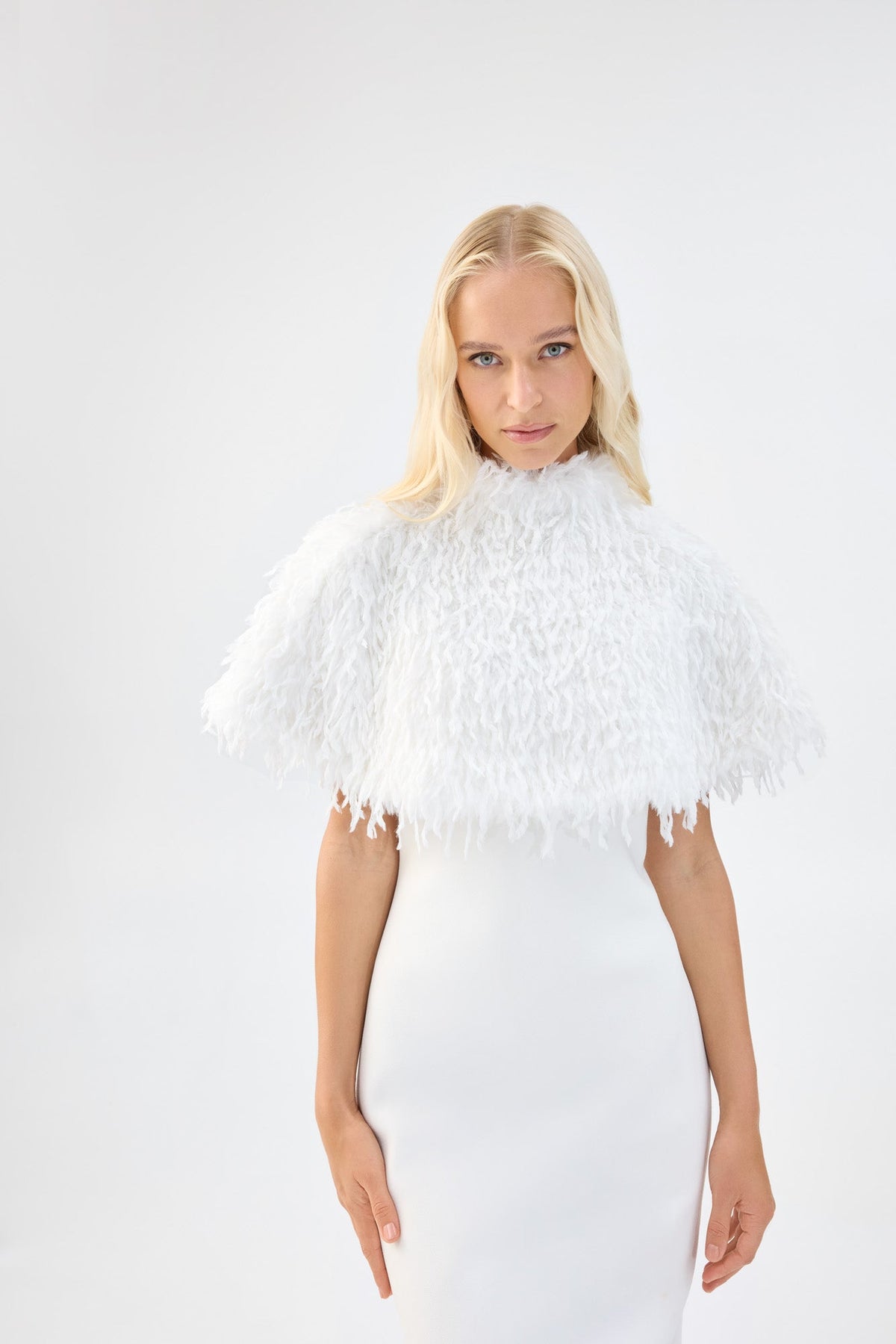 A model wearing a white textured faux fur bridal cape over a white gown.