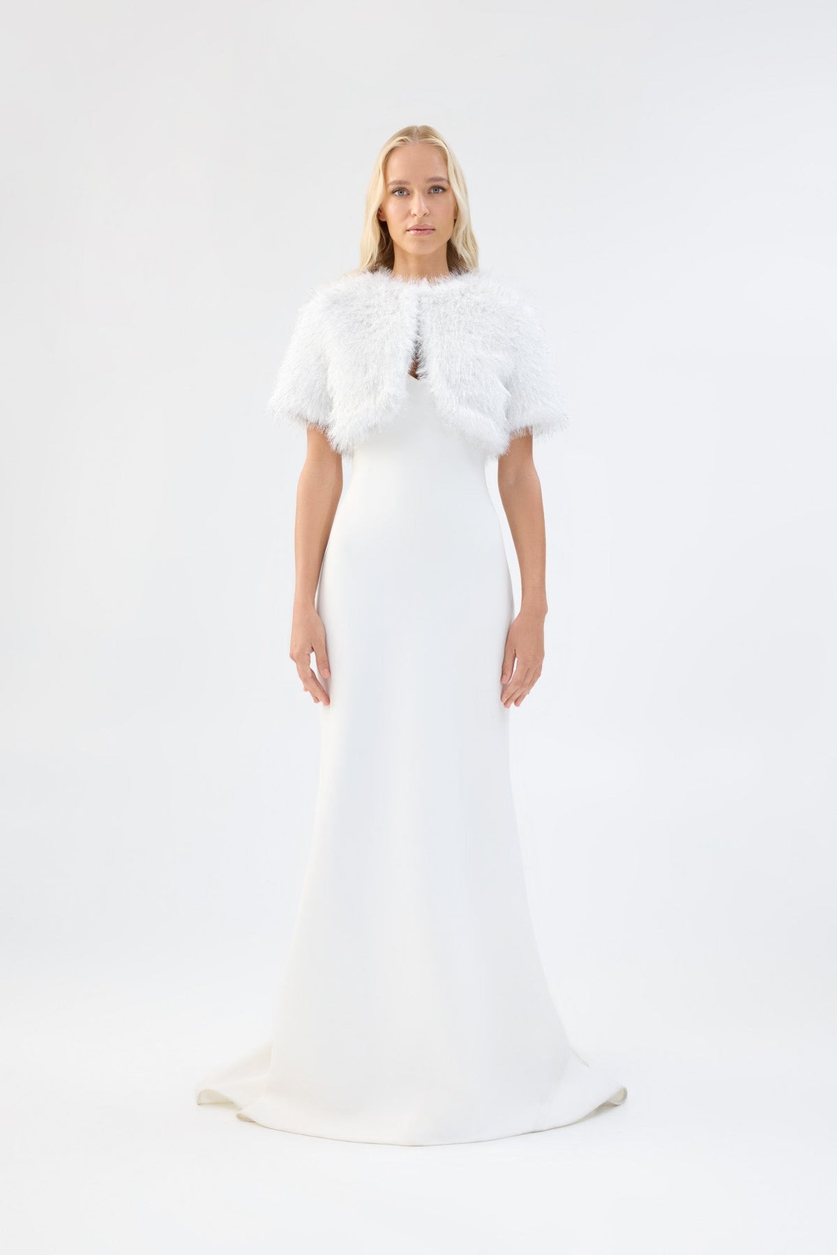 A model viewed from the front wearing a metallic white short-sleeve faux fur bridal bolero.
