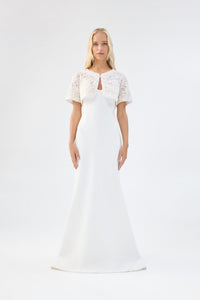 A model viewed from the front wearing a white floral textured bridal bolero over a white gown.