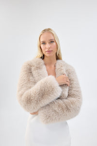 A close-up of a model wearing a cream faux fur bridal cropped jacket.