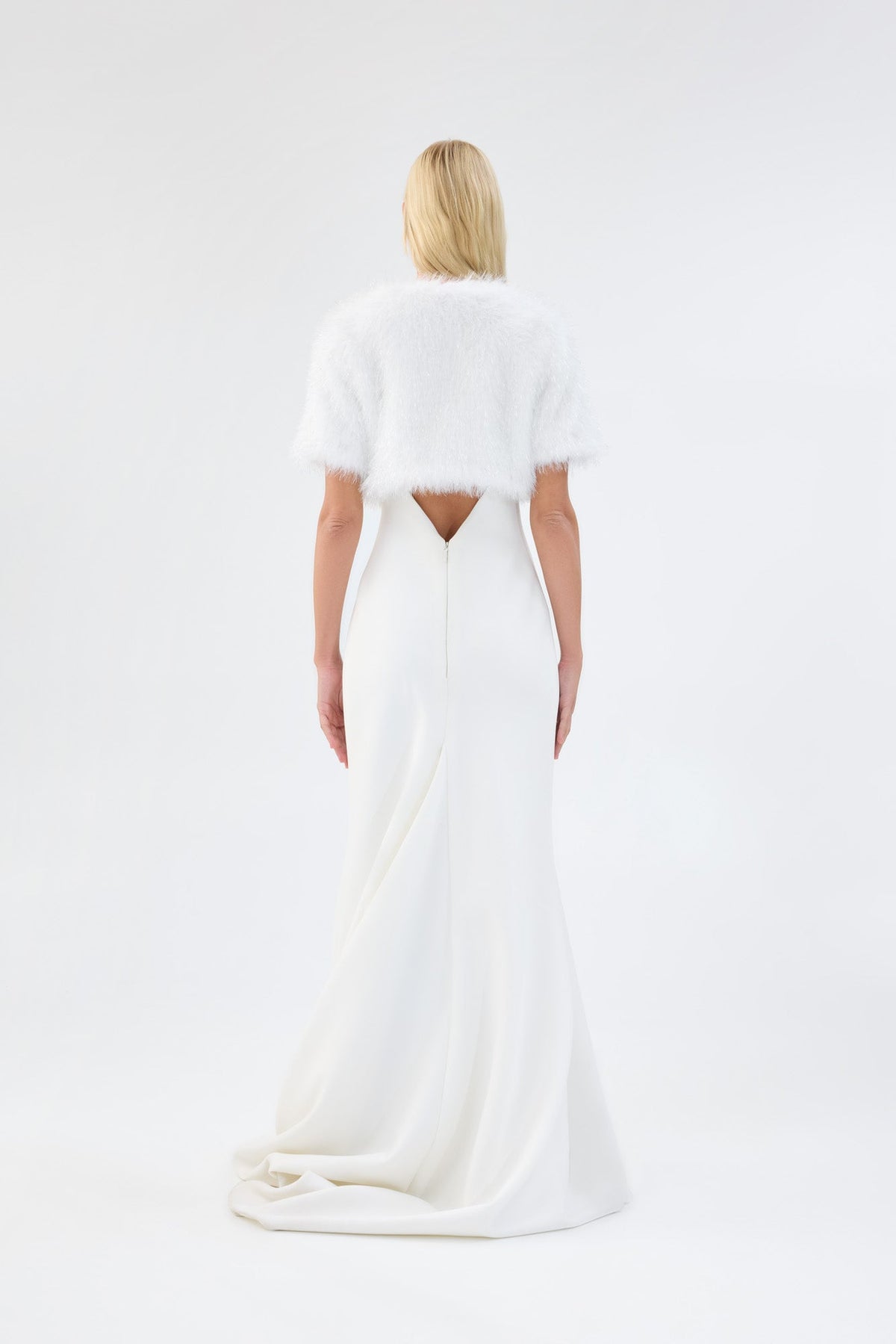 A model viewed from the back wearing a metallic white short-sleeve faux fur bridal bolero.
