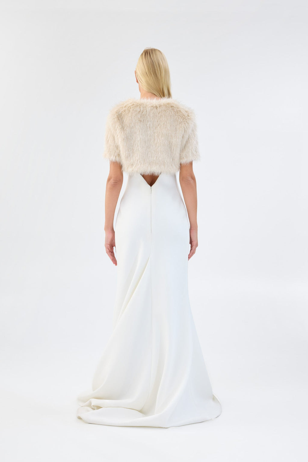 A model viewed from the back wearing a metallic cream short-sleeve faux fur bridal bolero.