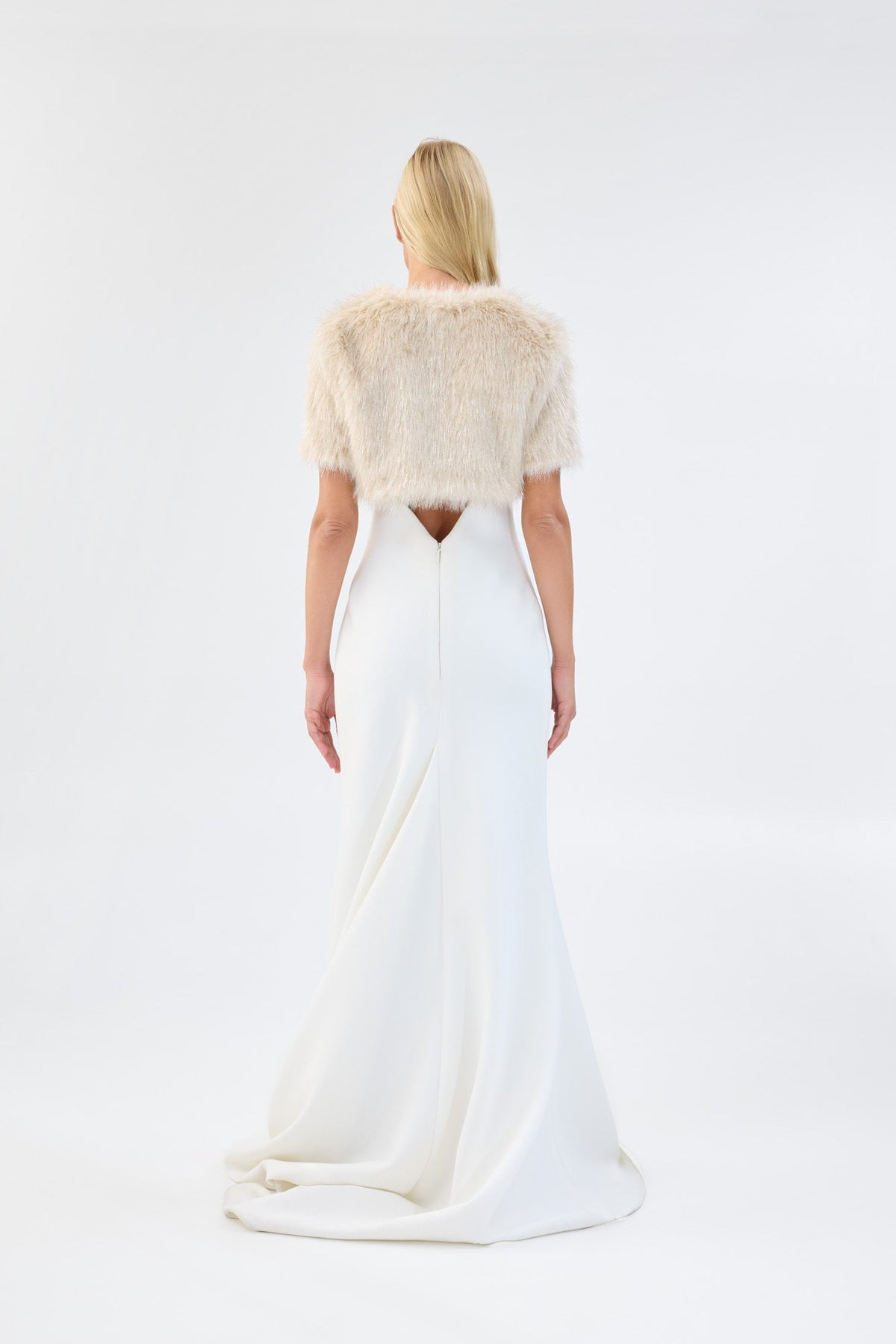 A model viewed from the back wearing a metallic cream short-sleeve faux fur bridal bolero.