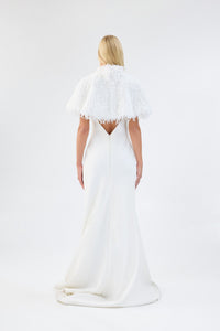 A model viewed from the back wearing a white textured faux fur bridal cape over a white gown.